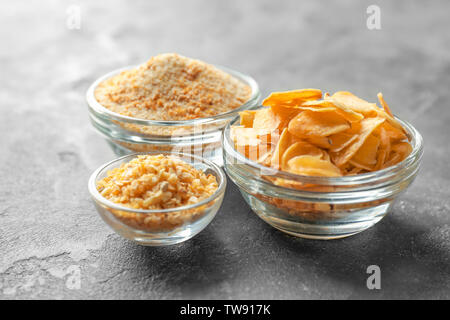 Getrockneten Knoblauch Flocken, Granulat und Pulver in Glasschalen auf grauem Hintergrund Stockfoto