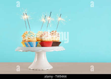 Geburtstag Cupcakes mit Wunderkerzen auf Dessert gegen Farbe Hintergrund Stockfoto