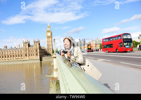 London reisen, Frau touristische von Big Ben und roten Doppeldeckerbusses. Mädchen mit Foto auf die Westminster Bridge mit smart phone Kamera über die Themse, London, England, Großbritannien, Großbritannien. Stockfoto