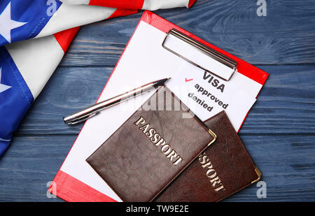 Pässe mit Zwischenablage und USA-Flagge auf Holz- Hintergrund. Genehmigte American Visa Stockfoto