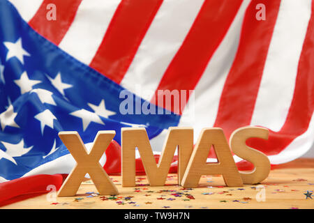 Wort Weihnachten aus Holz Buchstaben auf dem Tisch gegen verwackelte Amerikanische Flagge Stockfoto