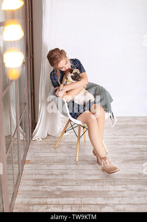 Junge Frau mit niedlichen Mops Hund zu Hause. Pet Adoption Stockfoto