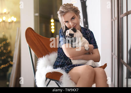 Junge Frau mit niedlichen Mops Hund zu Hause. Pet Adoption Stockfoto