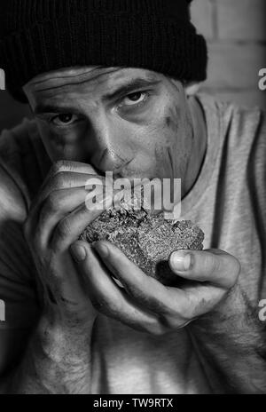 Hungrige arme Mann essen Stück Brot Stockfoto