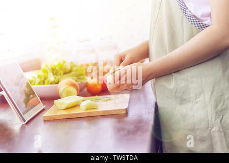 Asiatische Frau vorbereiten Zutaten zum Kochen folgen Kochen online Video Clip auf der Website über Tablet. Kochen Inhalte auf Internet Technologie für moderne Stockfoto