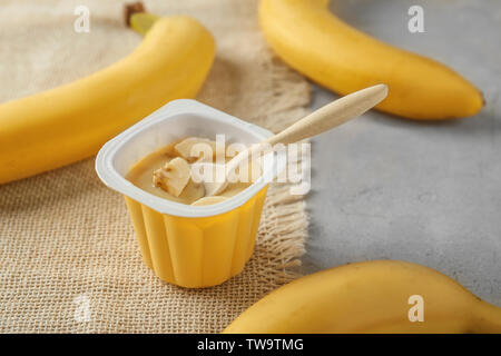 Schale aus Kunststoff mit lecker Banane Joghurt auf dem Tisch Stockfoto