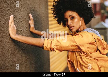 Gute junge afrikanerin, die sich an der Wand dehnt. Fitnesstraining für Frauen am Morgen im Freien. Stockfoto