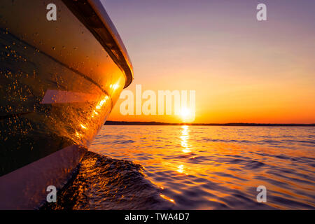 Seitenansicht Beschleunigung angeln Motorboot mit Tropfen Wasser. Blue Ocean Meer Wasser Welle Reflexionen an den Sonnenuntergang. Motorboot im blauen Ozean. Ozean ya Stockfoto