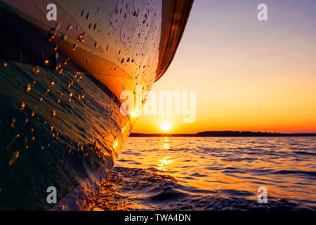 Seitenansicht Beschleunigung angeln Motorboot mit Tropfen Wasser. Blue Ocean Meer Wasser Welle Reflexionen an den Sonnenuntergang. Motorboot im blauen Ozean. Ozean ya Stockfoto