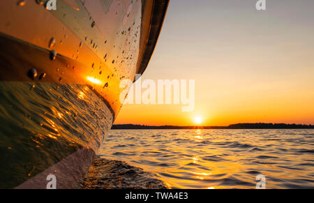 Seitenansicht Beschleunigung angeln Motorboot mit Tropfen Wasser. Blue Ocean Meer Wasser Welle Reflexionen an den Sonnenuntergang. Motorboot im blauen Ozean. Ozean ya Stockfoto