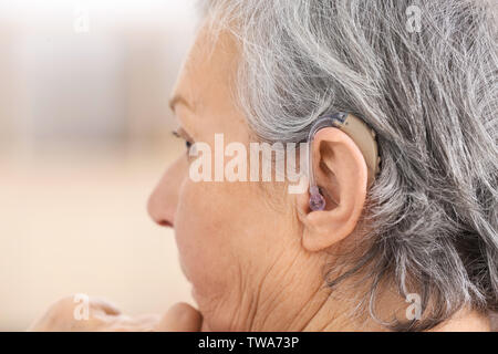 Reife Frau mit Hörgerät im Innenbereich Stockfoto