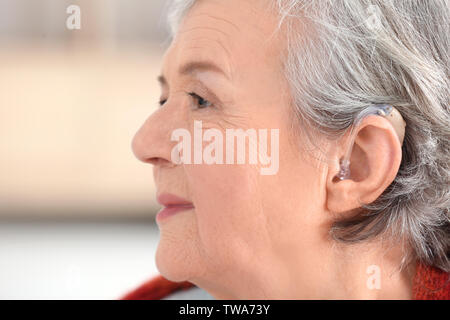 Reife Frau mit Hörgerät im Innenbereich Stockfoto