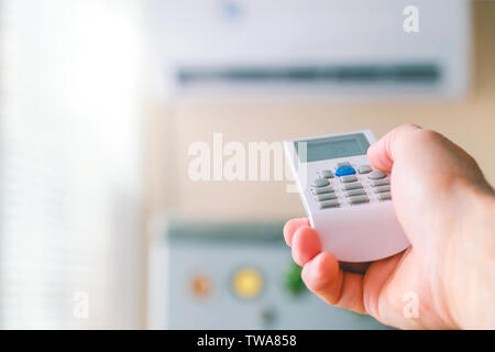 Fernbedienung. Männliche hand mit Klimaanlage Fernbedienung. Der Mann schaltet die Modi der Klimaanlage. Regelt die Temperatur des r Stockfoto