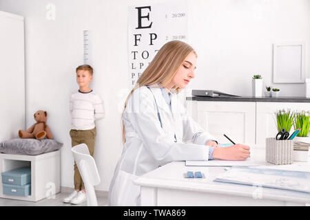 Junge weibliche Arzt notieren Sie sich die Ergebnisse nach der Messung des kleinen Jungen Höhe im Krankenhaus Stockfoto