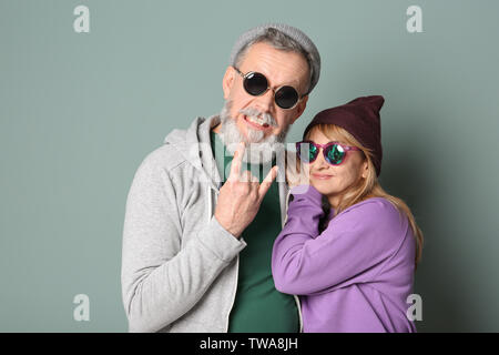 Gerne älteres Paar in hipster Outfits auf grauem Hintergrund Stockfoto