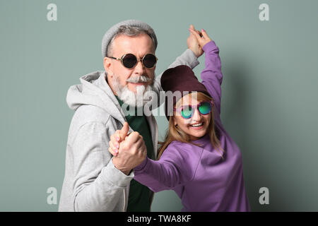 Gerne älteres Paar in hipster Outfits auf grauem Hintergrund Stockfoto