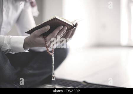Junge muslimische Mann lesen Koran, innen Stockfoto