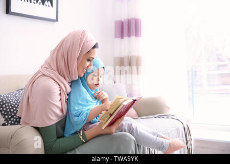 Muslimische Frau lesen Quran zu ihrer Tochter zu Hause Stockfoto