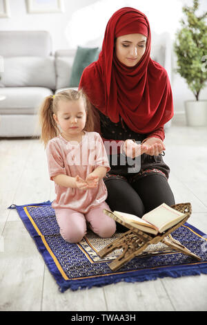Muslimische Frau mit ihrer Tochter zu Hause beten Stockfoto