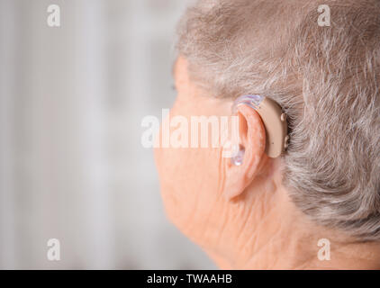 Ältere Frau mit Hörgerät im Innenbereich Stockfoto