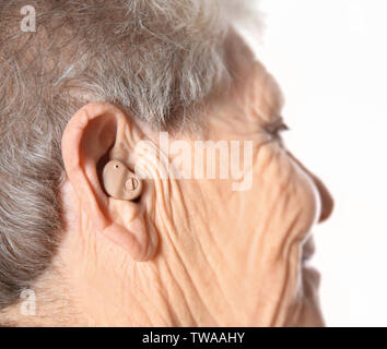 Ältere Frau mit Hörgerät auf weißem Hintergrund Stockfoto