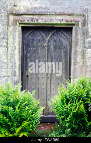 Eine geschlossene rustikale Holzgartentür in einer rustikalen Wand. Stockfoto