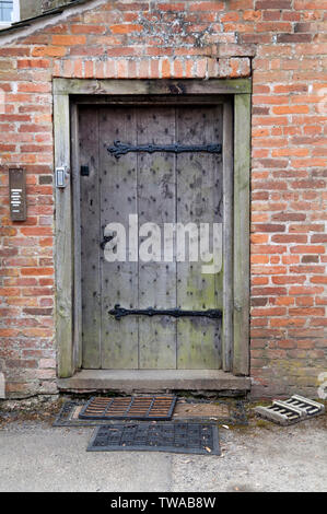 Eine geschlossene rustikale Holzgartentür in einer rustikalen Wand. Stockfoto