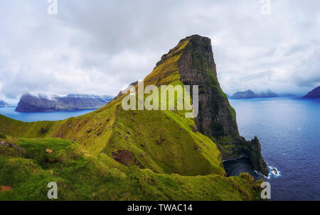 Kleine Leuchtturm in der Nähe von riesigen Felsen auf der Insel Kalsoy, Färöer Inseln Stockfoto