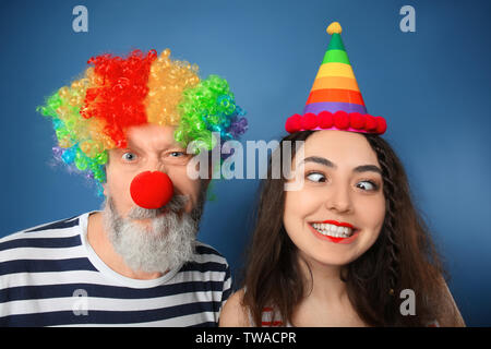 Junge Frau und reifer Mann in lustig auf Farbe Hintergrund verschleiern. April Fool's Day Feier Stockfoto