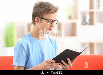 Teenager mit Hörgerät lesen Buch drinnen Stockfoto