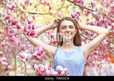 Porträt der schöne junge Frau in der Nähe von blühenden Magnolienbaum im Freien Stockfoto