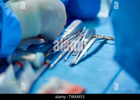 In der Nähe von Doktor Hände während der Operation in Betrieb. Sterilen chirurgischen Instrumenten in einem realen Betrieb verwendet. Schwerpunkt liegt auf der Zeile der Klemmung Griffe. Stockfoto