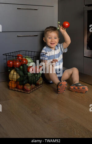 Kleines Kind spielt mit frischem Gemüse in der Küche Stockfoto