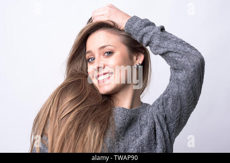 Beauty Portrait von jungen hübschen Frau mit langen gesundes Haar posing und lächelnd auf hellgrauem Hintergrund. Stockfoto