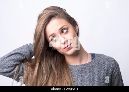 Nette junge nachdenkliche Frau bürsten Haare auf hellgrauem Hintergrund suchen. Stockfoto