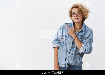 Verdächtig ist, was Sie denken. Portrait von zweifelhaft, unsicher und zögerlich gut aussehende stilvolle Freundin in Jeans Jacke und Brille schürzte Kinn in Stockfoto