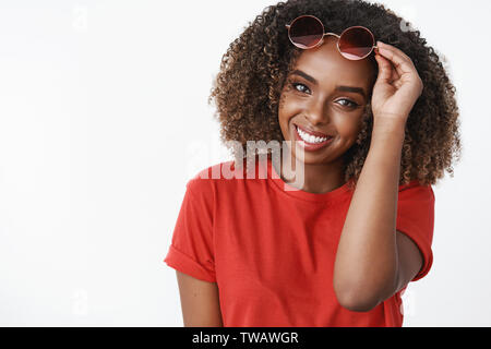 Mädchen unter der Sonnenbrille als Gespräch mit netten Typen kommend in Richtung lächelnd flirty und Schöne an Kamera, Brille auf der Stirn tragen rote t zu begrüßen Stockfoto