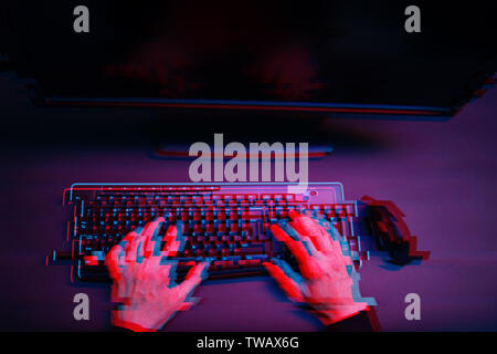 Hacker in der Haube arbeiten mit computer Eingeben von Text in dunklen Zimmer. Bild mit glitch Wirkung Stockfoto