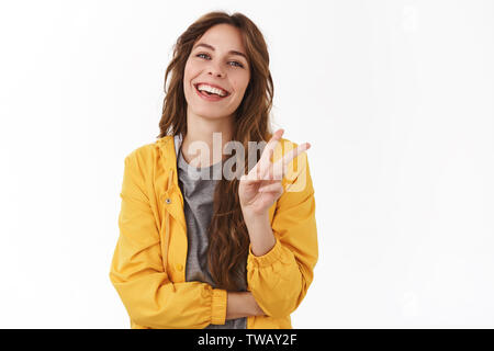 Frieden Freunde. Fröhlich begeistert wunderschöne Mädchen curly Kastanie Frisur show Sieg Geste lächelnd lachend sorglos in Auftakt optimistisch Stockfoto