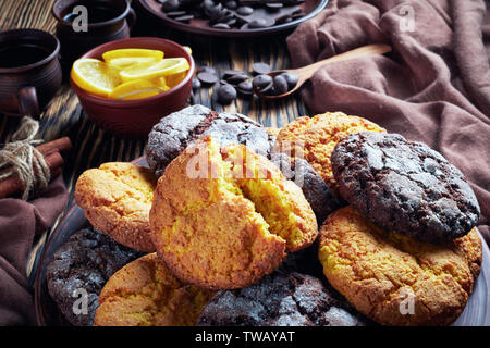 Crinkle Cookies. Zitrone und Schokolade Kekse auf einem Steingut Teller auf einem rustikalen Holztisch mit Zutaten geknackt, Ansicht von oben, close-up Stockfoto
