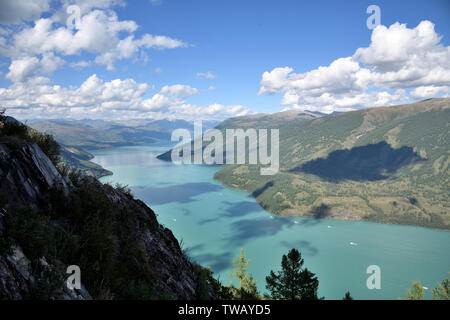 Im August 2018 in Kanas See, Xinjiang, Kanas See unter dem blauen Himmel und weißen Wolken fotografiert, wie ein riesiges Sapphire mit Intarsien zwischen den Gipfeln. Stockfoto