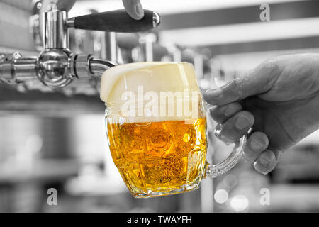 Ein Mann gießen Fass Bier in eine genoppte Glas Becher in ein modernes Pub. Überquellenden Glas. Schwarzen und weißen Hintergrund. Stockfoto