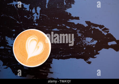 Cappuccino in einem Papier nehmen Schale auf Peeling und Risse in Schwarz und Violett lackiertem Holz von oben isoliert. Platz für Text. Stockfoto
