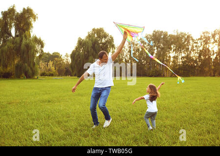 Glückliche Familie Vater und Kind laufen auf Wiese mit einem Drachen im Sommer auf der Natur Stockfoto