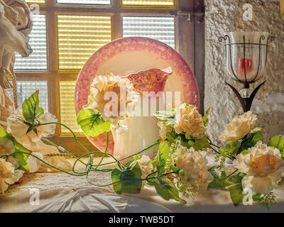 Stillleben mit feinen gelben Rosen, Glas Kerzenständer, einem alten aufrecht stehende Platte mit rosa Blume Grenze, vor der eine dazu passende Wasser Karaffe in Stockfoto