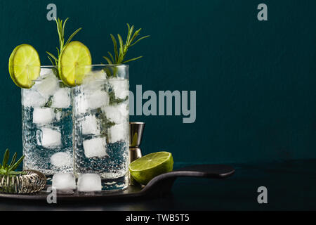 Classic Gin und Tonic Cocktail mit rosmarinzweige in hohe Gläser auf einem Tisch mit bar Zubehör Stockfoto