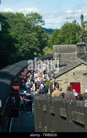 Eine Masse von Fluggästen auf der Plattform neben dem Dampfzug an Haworth Bahnhof, auf Keighley und Worth Valley Railway Stockfoto