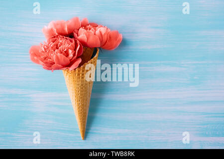 Pfingstrosen coral Farbe. Ein Strauß Pfingstrosen in einem Kegel für Speiseeis. Farbe 2019. Kreatives Design. Minimalismus. Stockfoto
