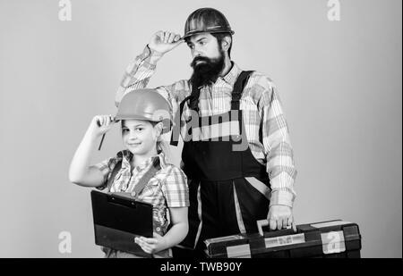 Vater und Tochter in der Werkstatt. Bärtiger Mann mit kleines Mädchen. Bauarbeiter assistant. Builder oder Tischler. Handwerker in Uniform. Ingenieur. Reparieren. Kinder Kreativität. Team bei der Arbeit. Stockfoto