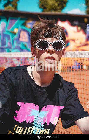 Porträt eines jungen Mannes mit Sonnenbrille entspannende gegen Graffiti Hintergrund im Freien Stockfoto